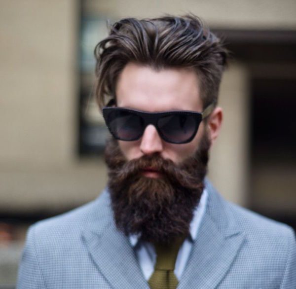 homem de traje passeio completo, com óculos de sol roxo e barba lenhador